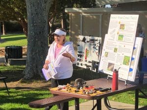 A professional woman presenting drip irrigation techniques at an outdoor workshop.